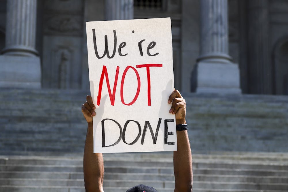 <p>A student lifts a sign saying "We're Not Done" during the walkout on April 5, 2023. Students from the University of South Carolina marched from Davis Field to the Statehouse to demonstrate their desire to protect student workers and student-athletes and make their voices heard.&nbsp;</p>