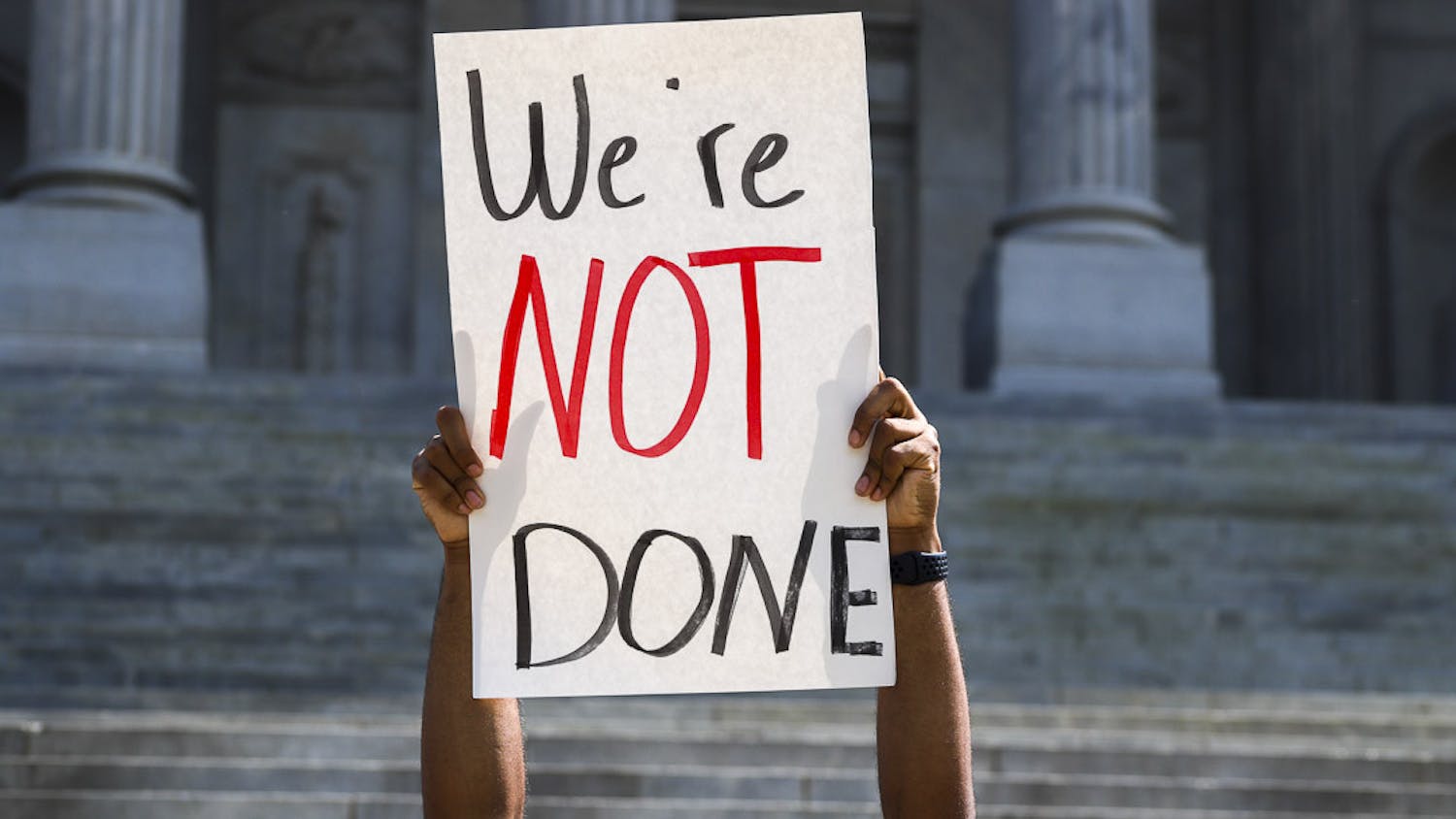 A student lifts a sign saying "We're Not Done" during the walkout on April 5, 2023. Students from the University of South Carolina marched from Davis Field to the Statehouse to demonstrate their desire to protect student workers and student-athletes and make their voices heard.&nbsp;