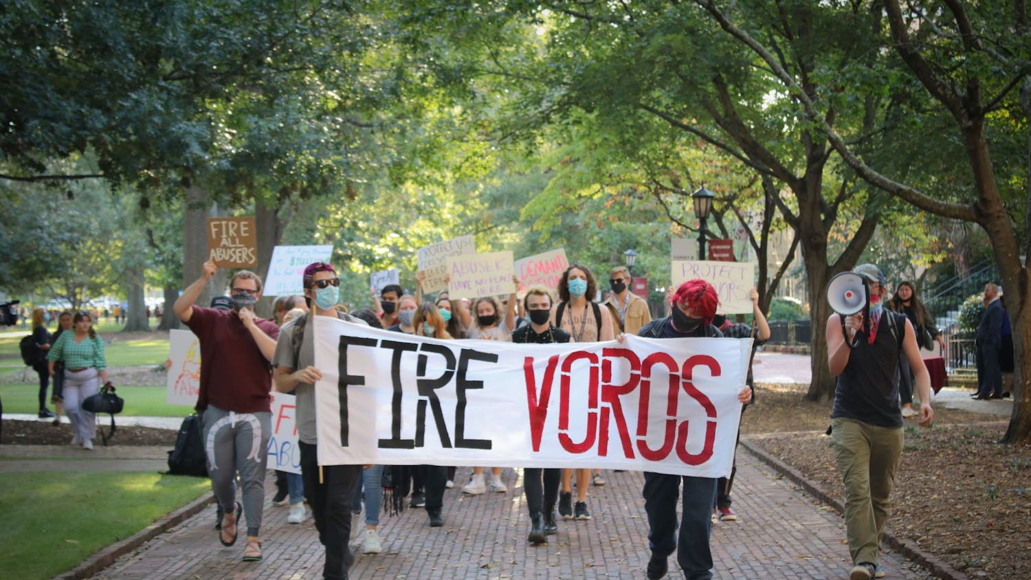 Protestors walk down the Horseshoe holding a sign that reads, 'FIRE VOROS.' USC students, faculty and staff protest the university's handling of the sexual assault allegations against professor David Voros and other alleged abusers.&nbsp;
