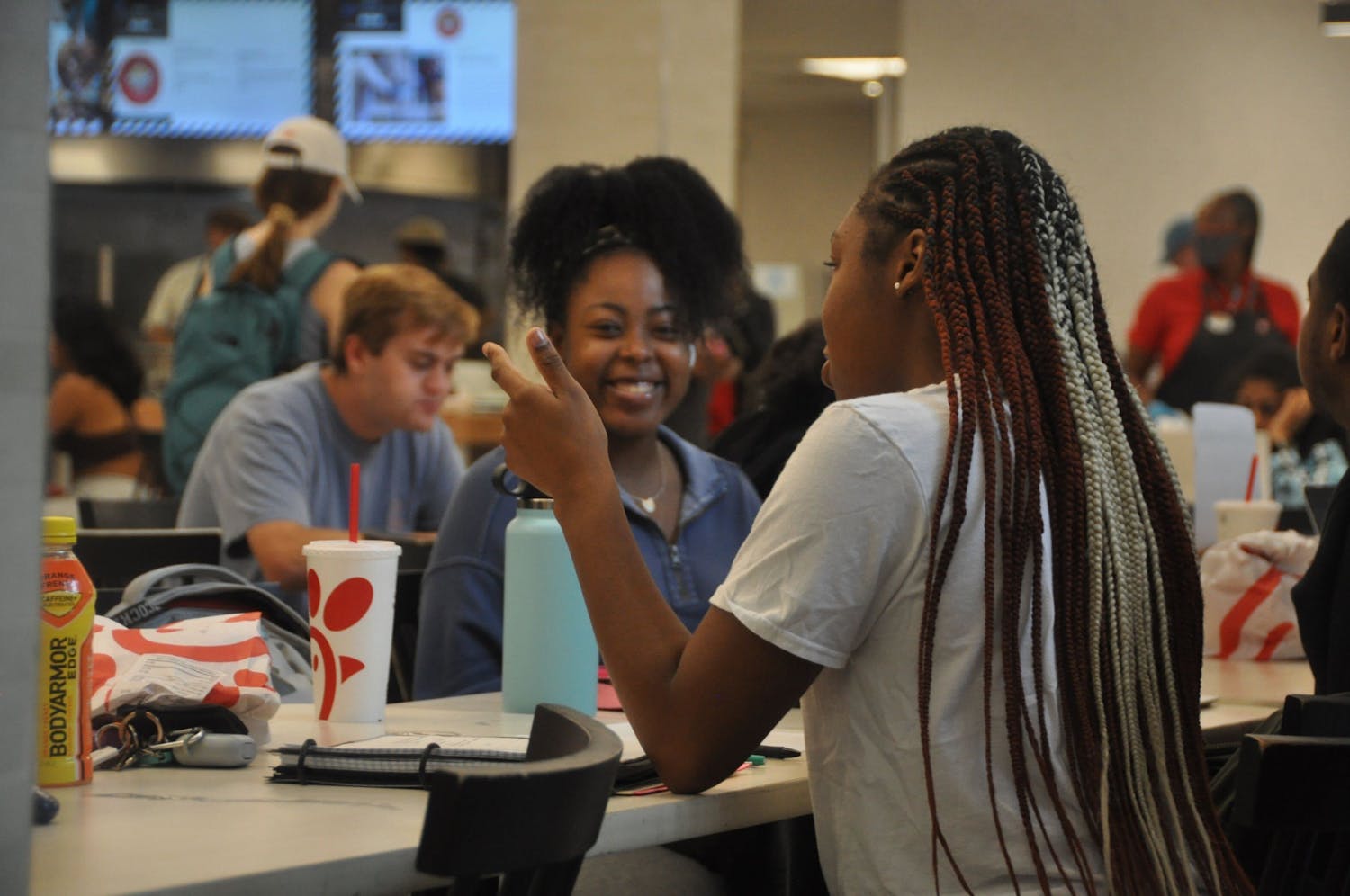 Two Black students hanging out at the community table on the first floor of Russell House. Many Black students feel this table gives them a way to show up on campus and be a part of a legacy of other students who have sat at the table, too.