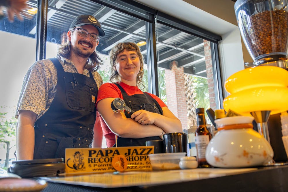 <p>Godspeed Coffee pop-up co-owners Roger Caughman (left) and Kailey Cunningham (right) pose for a photo on Aug. 17, 2024. The pair operates their shop in a shared storefront with Papa Jazz Record Shoppe on Saluda Avenue in Five Points.</p>