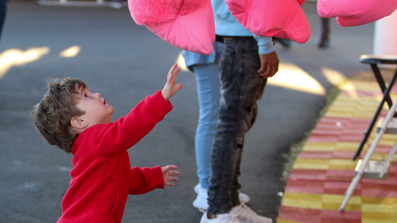 A young boy reaches for a giant pink gorilla hanging outside one of the many carnival games featured at the South Carolina State Fair on Oct. 21, 2022. The water ballon popping game awards animal and popular culture themed prizes to individuals who can win the game.