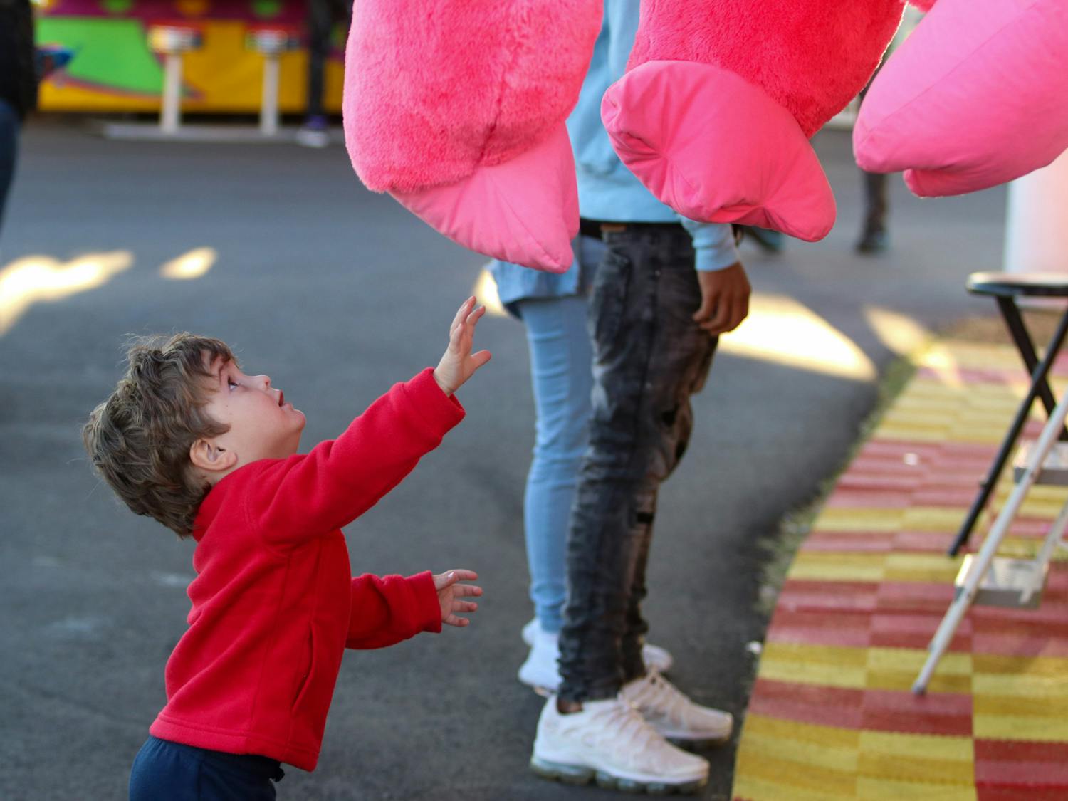 A young boy reaches for a giant pink gorilla hanging outside one of the many carnival games featured at the South Carolina State Fair on Oct. 21, 2022. The water ballon popping game awards animal and popular culture themed prizes to individuals who can win the game.