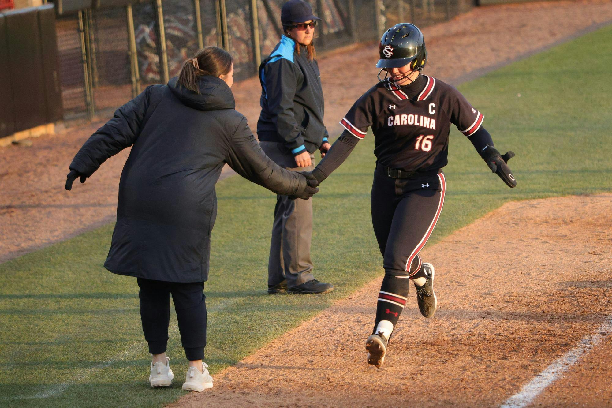 Senior infielder Arianna Rodi high-fives a coach after scoring during South Carolina's game against Winthrop on Feb. 8, 2026, at Carolina Softball Stadium. She crosses home plate in the Gamecocks’ 18–0 win.