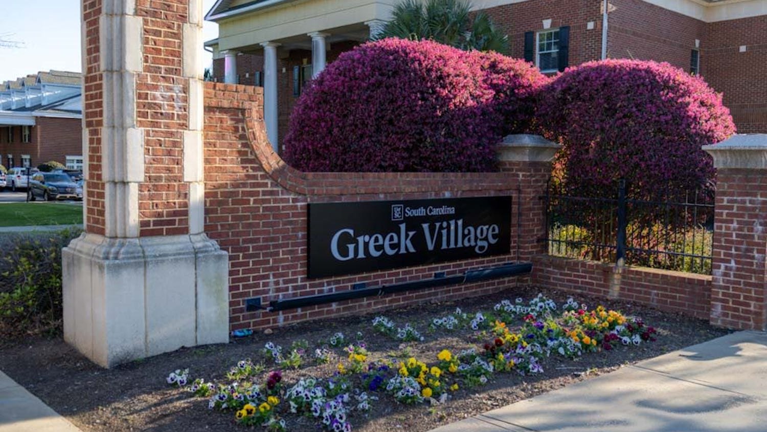 Outside of Greek Village on Blossom Street, the Greek Village sign is shown surrounded by its new bed of flowers on March 15, 2023. Greek Village is home to 13 sororities and seven fraternities that all have some variation of a meal plan.