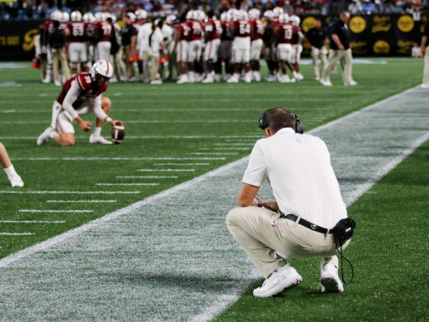 South Carolina head coach Shane Beamer squats on the sidelines during a break in play. The Gamecocks lost to the Tar Heels 31-17 on Sept. 2, 2023 in Charlotte, North Carolina.