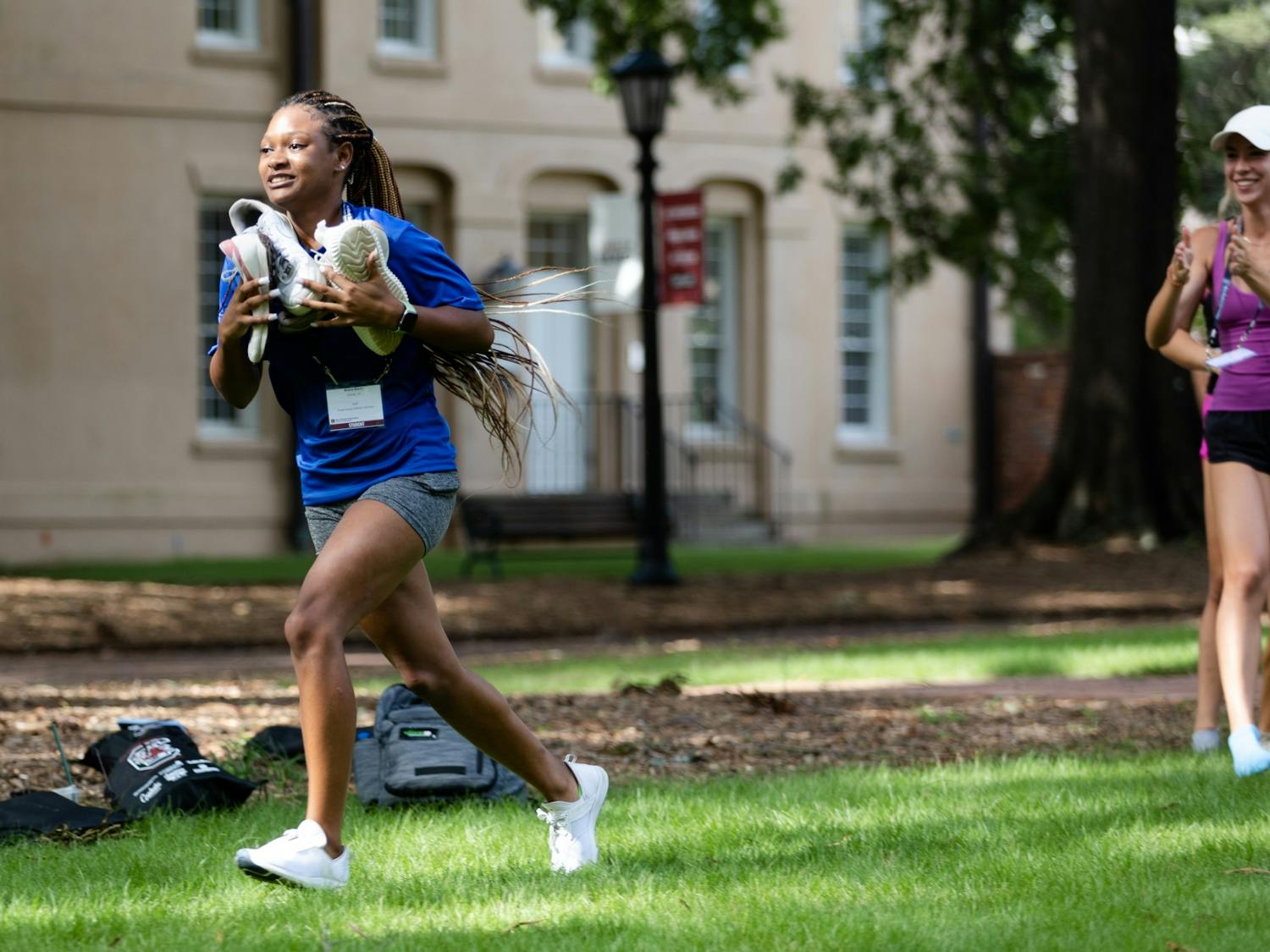 A first-year student runs toward her orientation leaders, attempting to be the first student to bring them four shoes. This game is played during orientation sessions throughout the summer to help new students have fun and make friends before starting their freshman year in the fall.