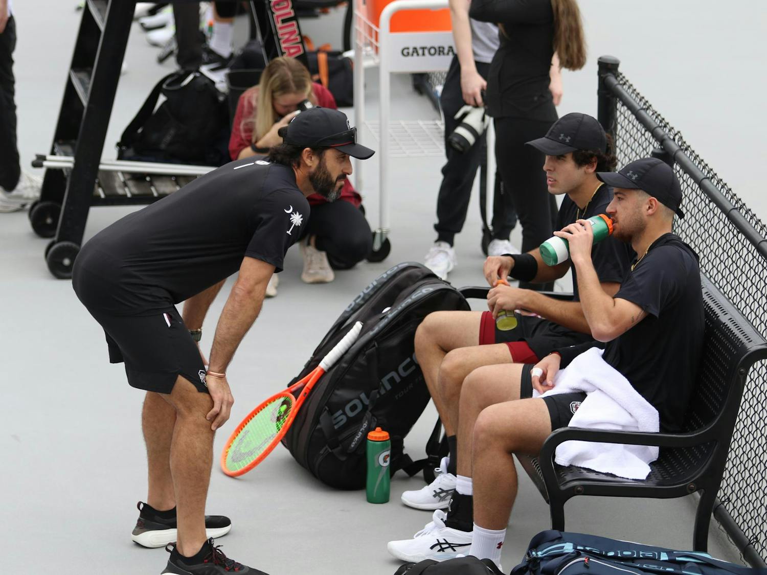 Head coach Josh Goffi talks to redshirt freshman Paul Barbier Gazeu and senior Lucas Andrade da Silva during their doubles match against Texas Feb. 27, 2026. The pair won their match against the Longhorns 6-4.