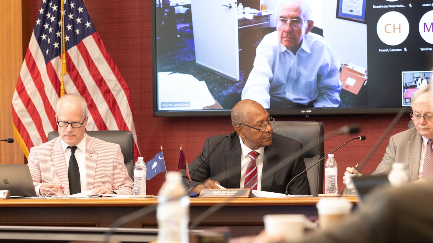 FILE — Secretary Cameron Howell (left) and trustee Alex English (middle) sit alongside USC President Michael Amiridis (right) at a board of trustees meeting on Aug. 18, 2023. The board approved a new research project, a new student advocacy center and a contract extension for head baseball coach Mark Kingston during the meeting.