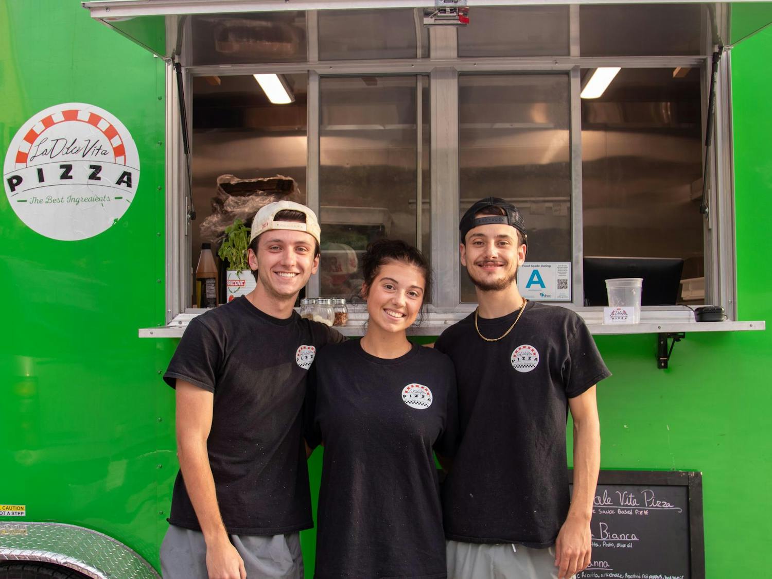 From left, Cook Logan Harris, Cashier Reanna Reed and owner Ben Petty pose for a picture in front of the La Dolce Vita Pizza food truck on Oct. 15, 2024. Petty said his favorite thing about owning the food truck is "serving people and seeing happy faces.”