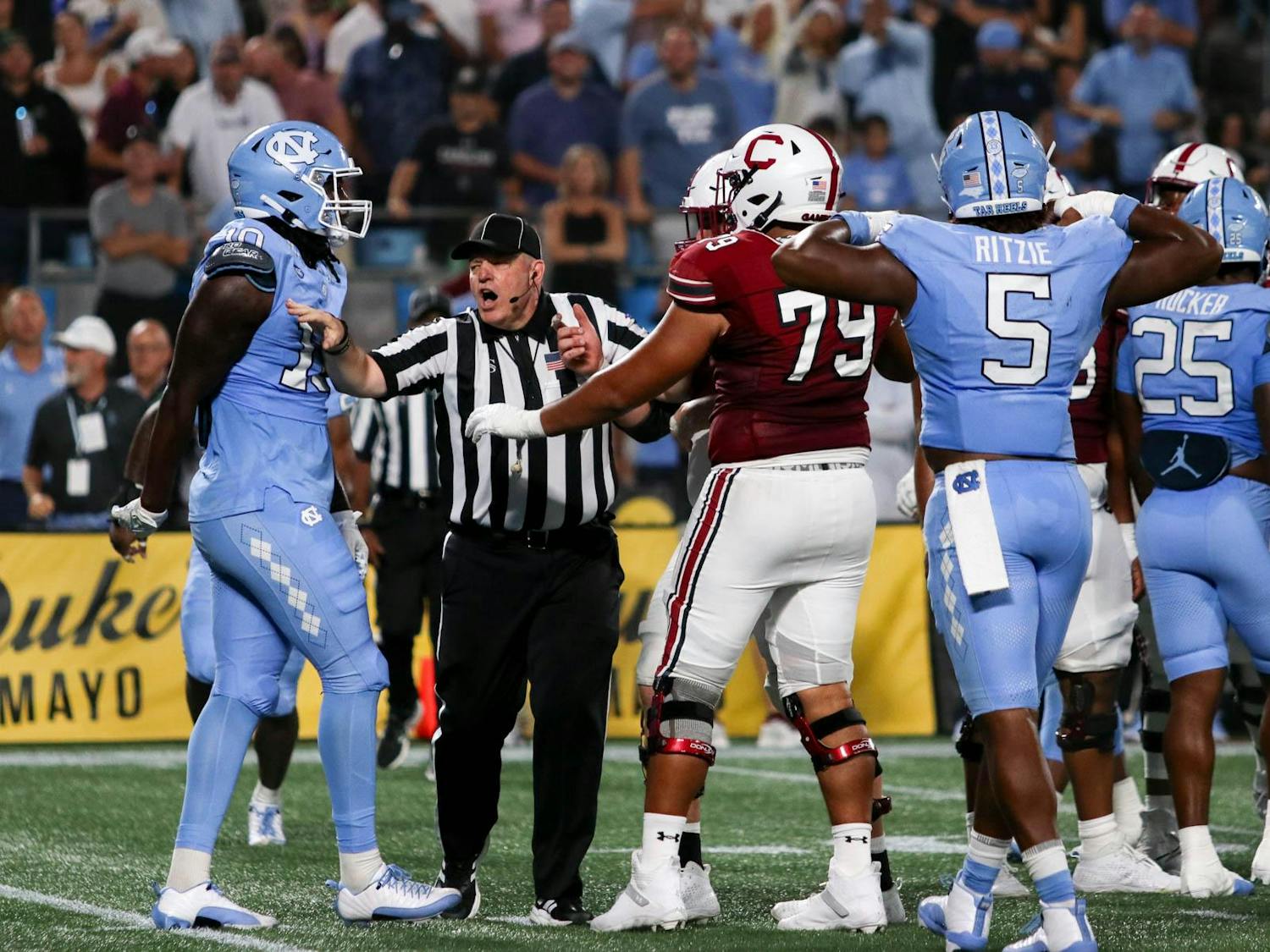 A referee breaks up an argument between players on the University of South Carolina and University of North Carolina football teams. North Carolina now leads the overall series between the two teams 36-20-4.