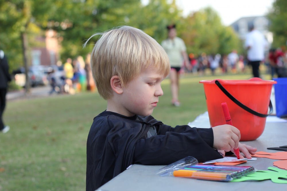Evan Johnson, whose father Tom works in the Public Health department, draws a face on a ghost at an arts and crafts stand.