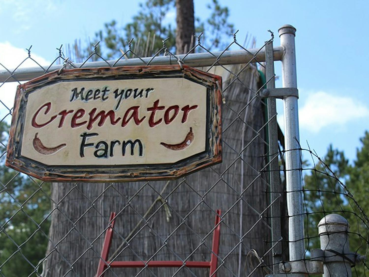 The sign for Meet Your Cremator Farm sits on the front gate. The farm grows peppers that are used to make some of its award-winning hot sauces.