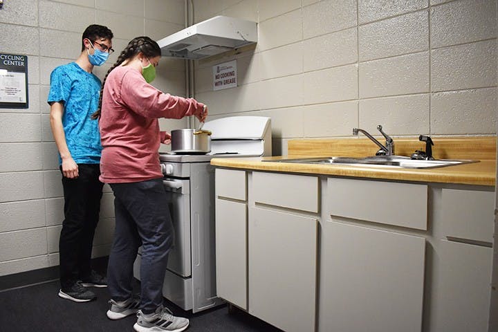 Capstone resident mentor Cecelia Tatro, third-year marketing and management student, and Nic Piazza, first-year civil engineering student, cook in a kitchen in Capstone. Capstone has four floors with kitchens spread throughout the building for residents to use.