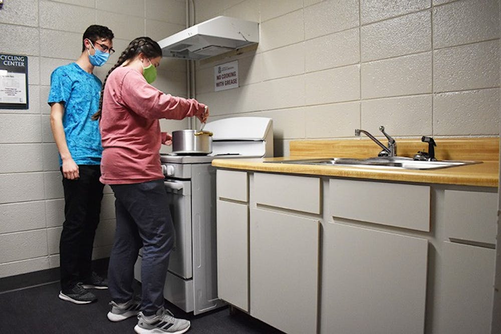 <p>Capstone resident mentor Cecelia Tatro, third-year marketing and management student, and Nic Piazza, first-year civil engineering student, cook in a kitchen in Capstone. Capstone has four floors with kitchens spread throughout the building for residents to use.</p>