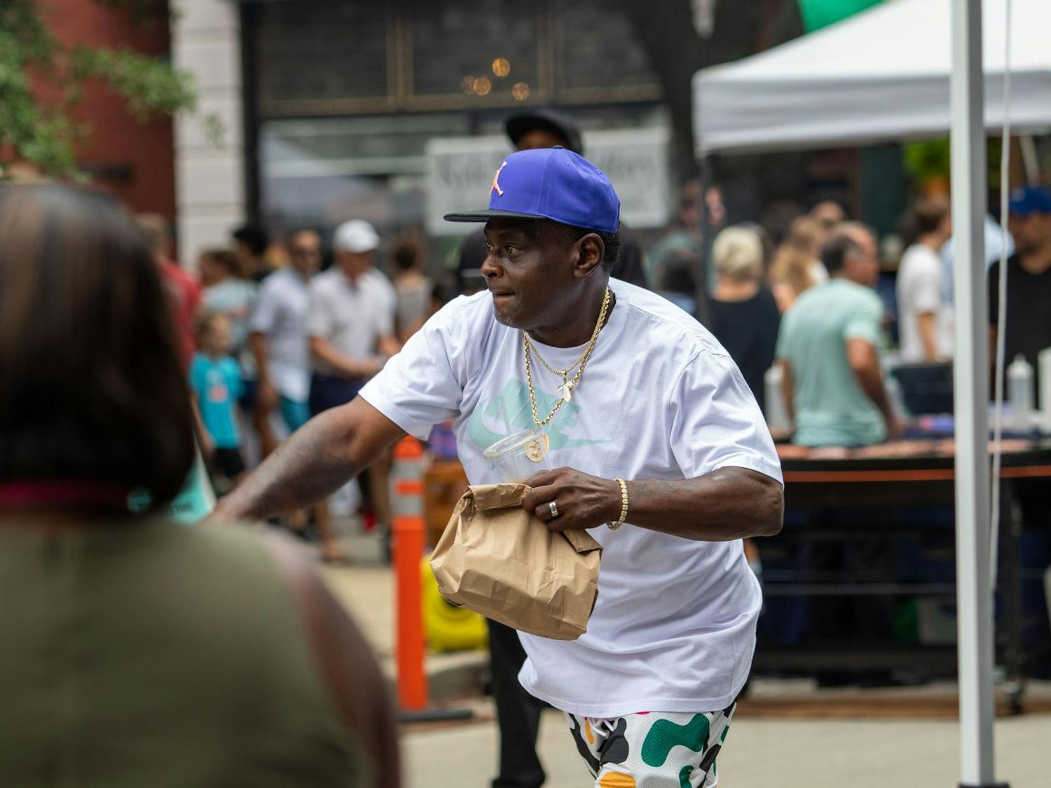 A participant throws the ball at the dunk booth while holding a bag in his hand at Soda City Market on July 27, 2024. Tickets for the dunk booth were $5 for three throws, $10 for seven throws, and $30 for an instant dunk.