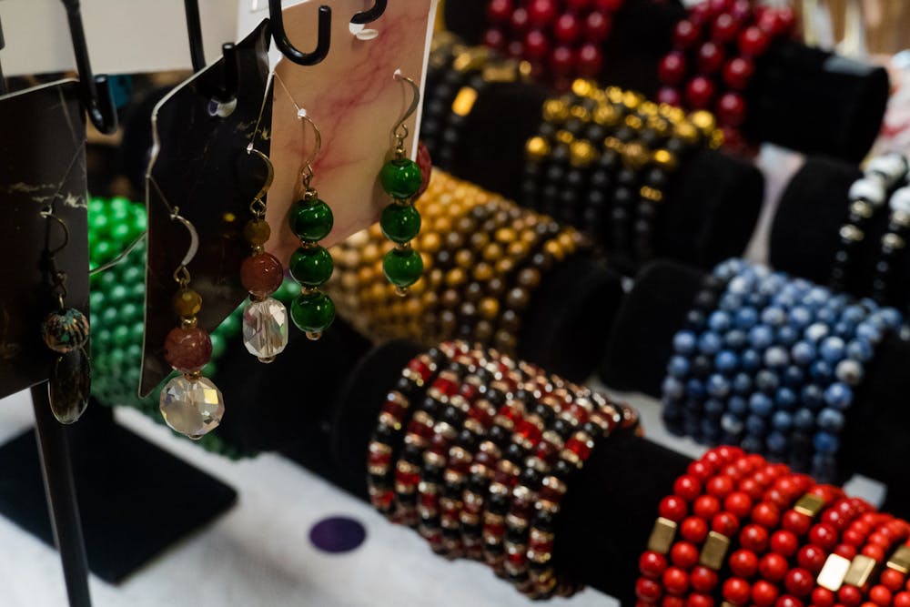 A variety of earrings hang over a collection of bracelets along a table in Unis Boutique on Oct. 10, 2022. The boutique located in 5 points sits directly above Baked Bear and serves as a destination for unique and original earrings, bracelets, shoes and clothing items.