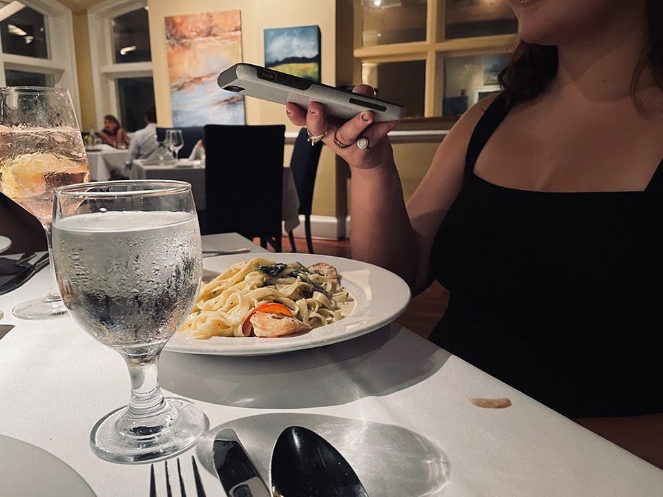 A person uses their phone to get a snapshot of their dinner served at a restaurant.&nbsp;