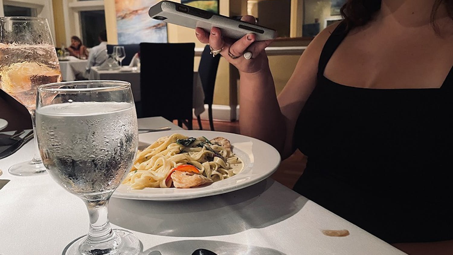 A person uses their phone to get a snapshot of their dinner served at a restaurant.&nbsp;