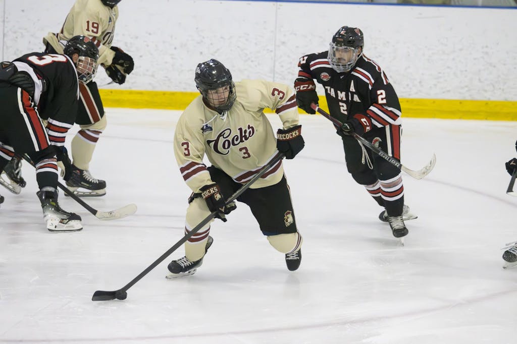 A player drags the puck along the ice as he skates away from an opposing player. 