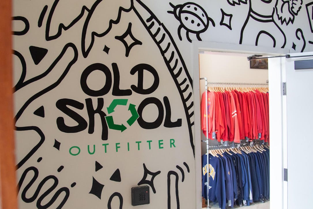 The outside entrance of Old Skool Outfitter with a mural on the wall with the words "Old Skool" in big bubble letters and "Outfitter" in a skinner font with different illustrations around it.