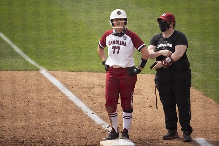 Junior infielder Kassidy Krupit stands at first base talking to one of her coaches.