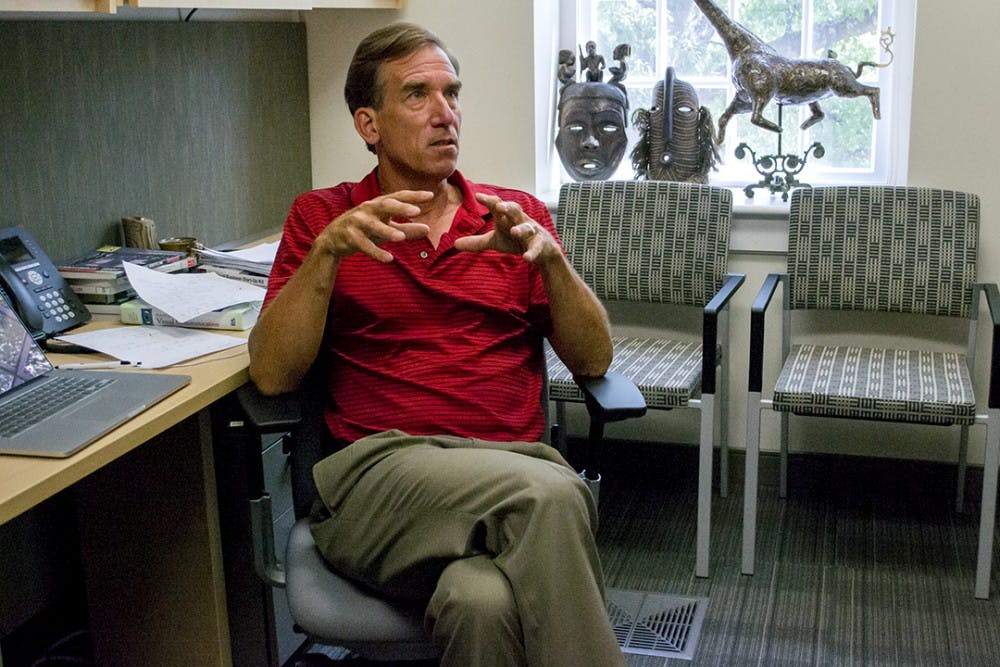 Keith Kenney displays a ceramic piece by his wife and authentic African art in his office in the journalism school.