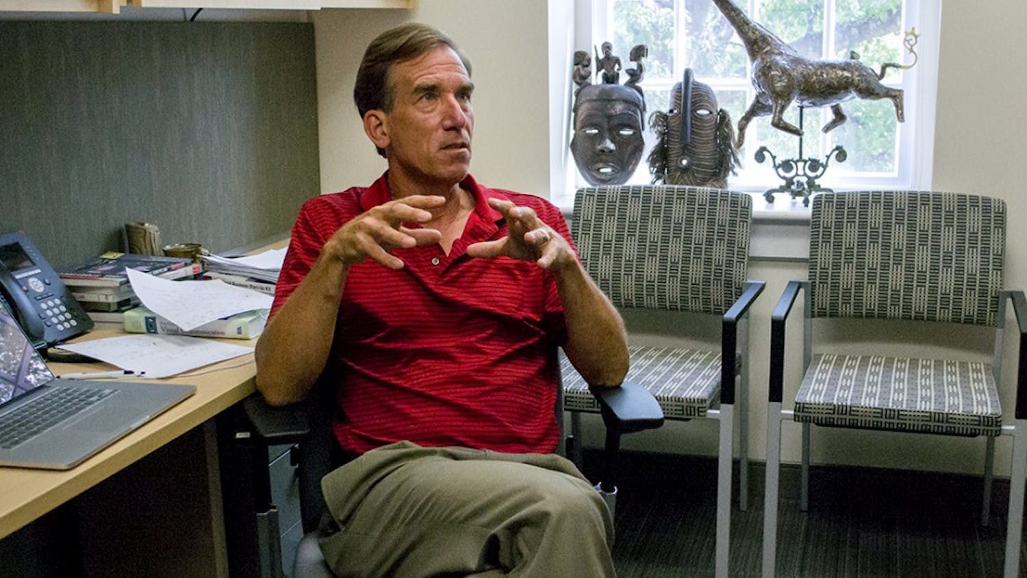 Keith Kenney displays a ceramic piece by his wife and authentic African art in his office in the journalism school.
