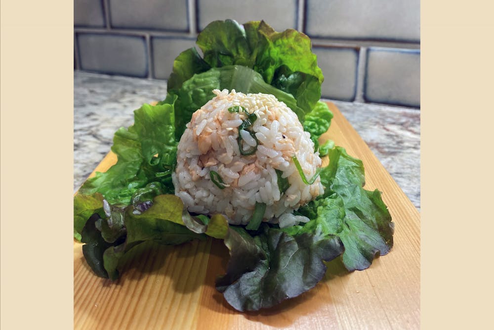 A rice ball made with sweet and savory salmon plated on a leaf of lettuce. Salmon rice balls are a quick and easy meal and perfect of a college student.