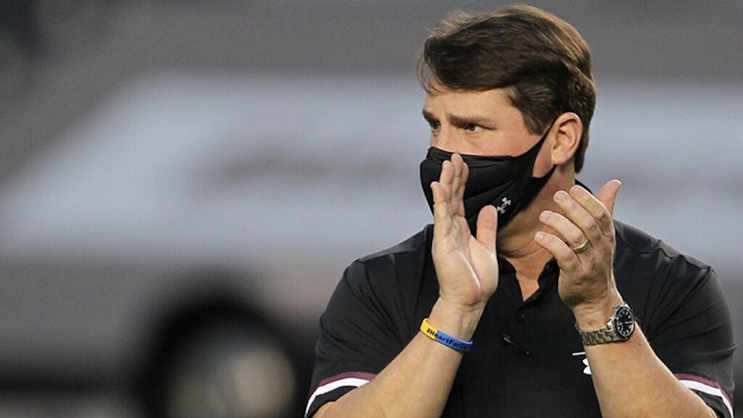 University of South Carolina football head coach Will Muschamp claps while walking down the sideline of the football game against the Tennessee Volunteers.
