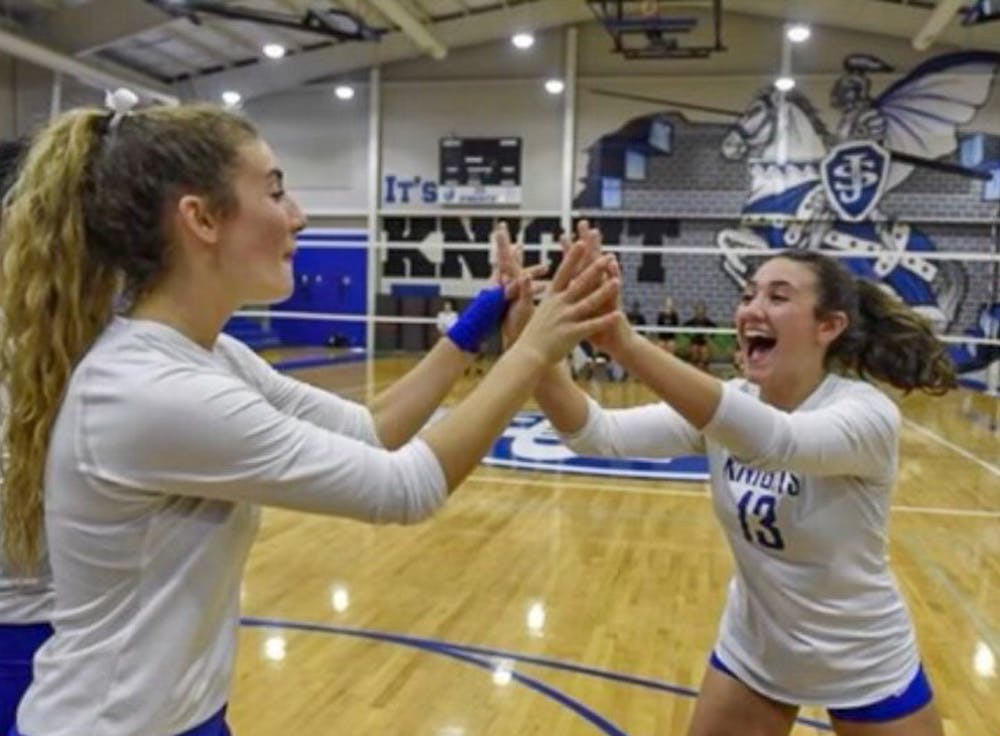 <p>Freshman setter Kimmie Thompson (on right) celebrates with a teammate during a match at Saint Joseph's Catholic School. Thompson played varsity for the junior/senior high school for five years, earning four 2A state titles and winning the state championships her senior year.</p>