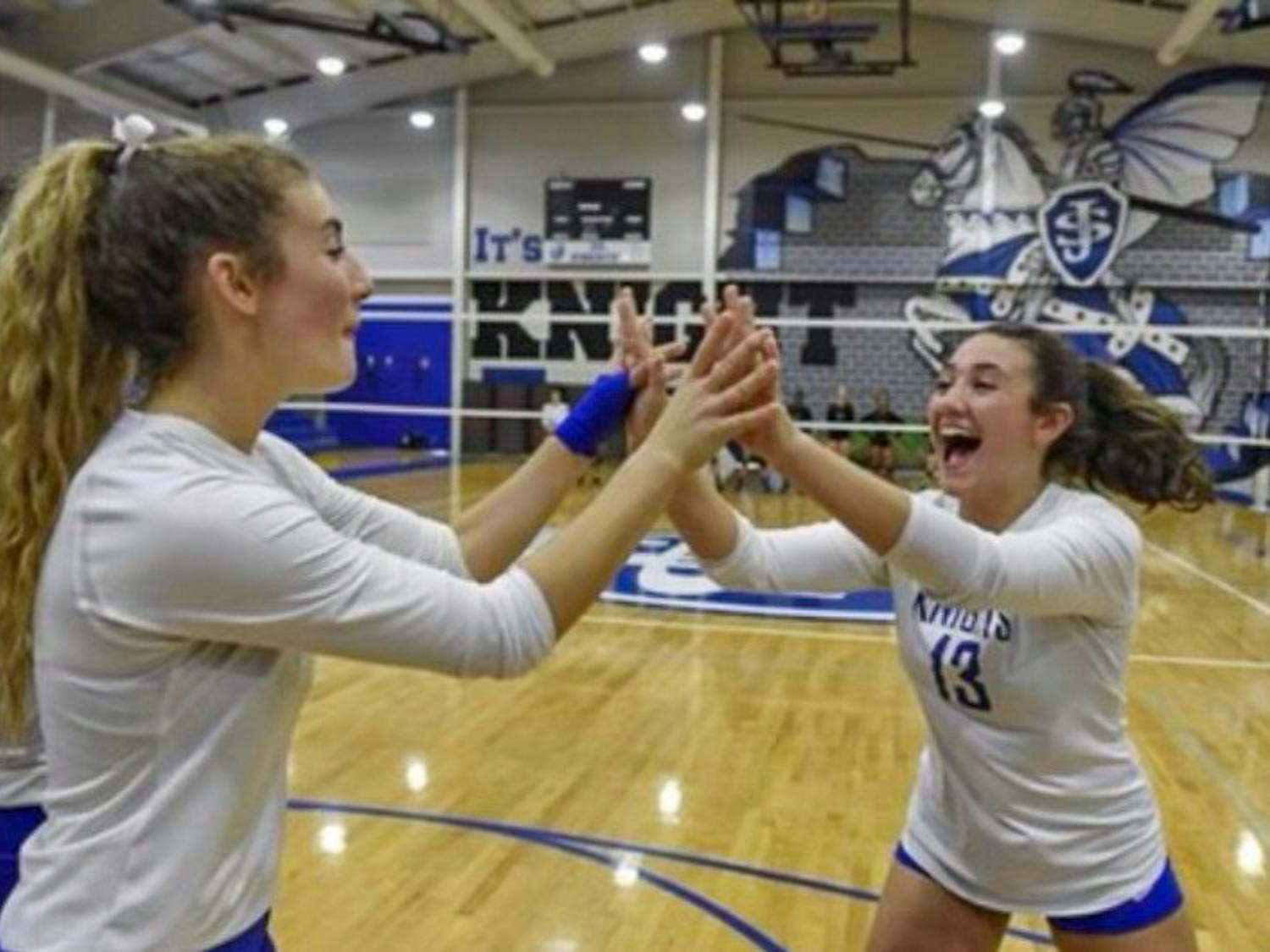 Freshman setter Kimmie Thompson (on right) celebrates with a teammate during a match at Saint Joseph's Catholic School. Thompson played varsity for the junior/senior high school for five years, earning four 2A state titles and winning the state championships her senior year.