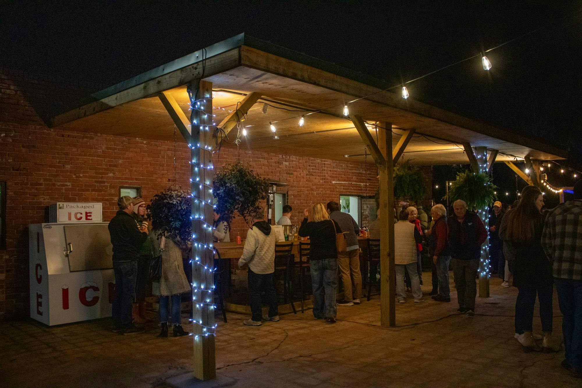 Attendees stand together outside underneath a wood overhang off a brick building. 