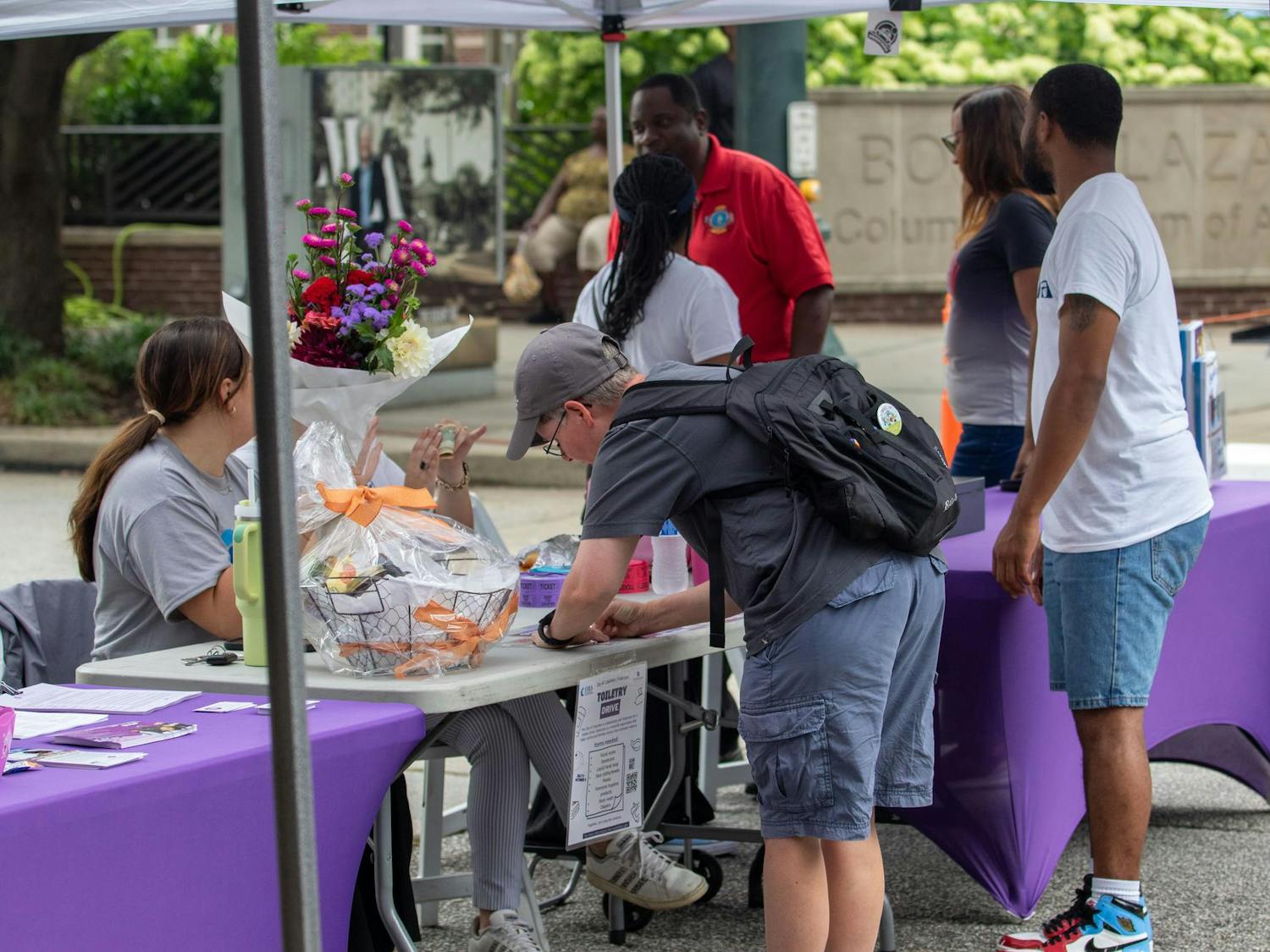 A participant giving money and signing up to throw the ball at the dunking booth at Soda City Market on July 27, 2024. During Sistercare Saturdays, participants paid money to dunk Columbia figures into a dunk booth.