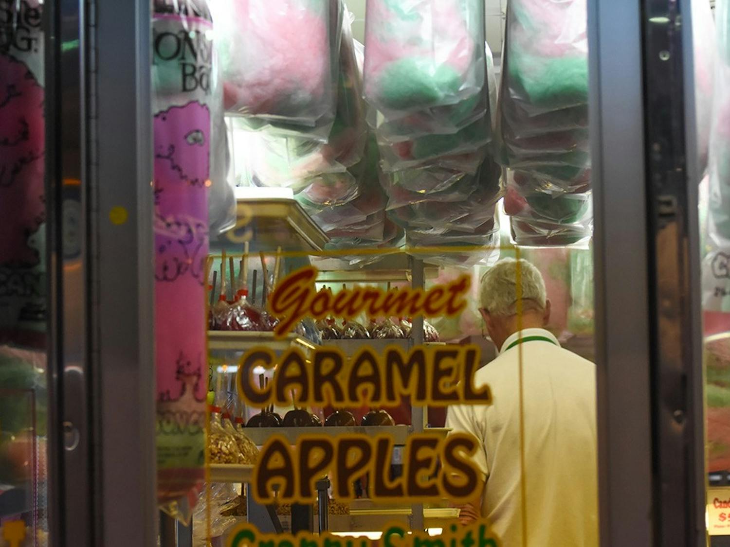A candymaker inside a food stand arranging caramel apples at the 152nd State Fair. He was one of many vendors who bake, cook or create food and beverages to sell to fair-goers.