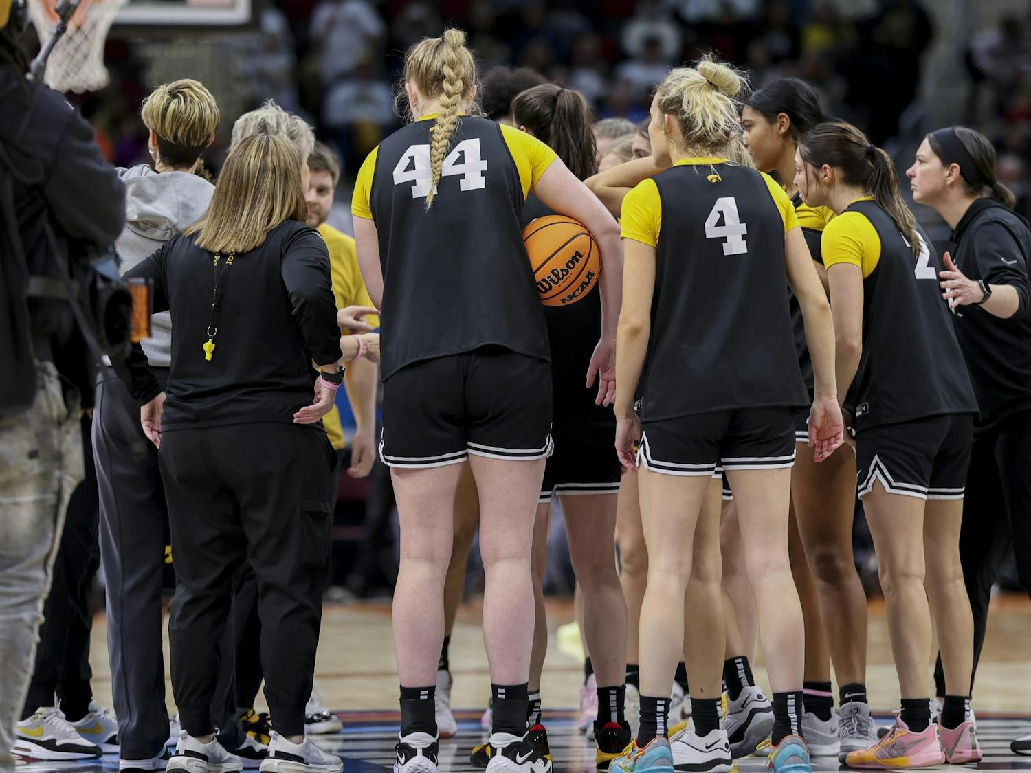 The Iowa Hawkeyes women's basketball team huddles in the center of the court in Rocket Mortgage FieldHouse on April 6, 2024. Following a team huddle, the team walked over to the spirit section and high-fived members of the Iowa Pep Band.