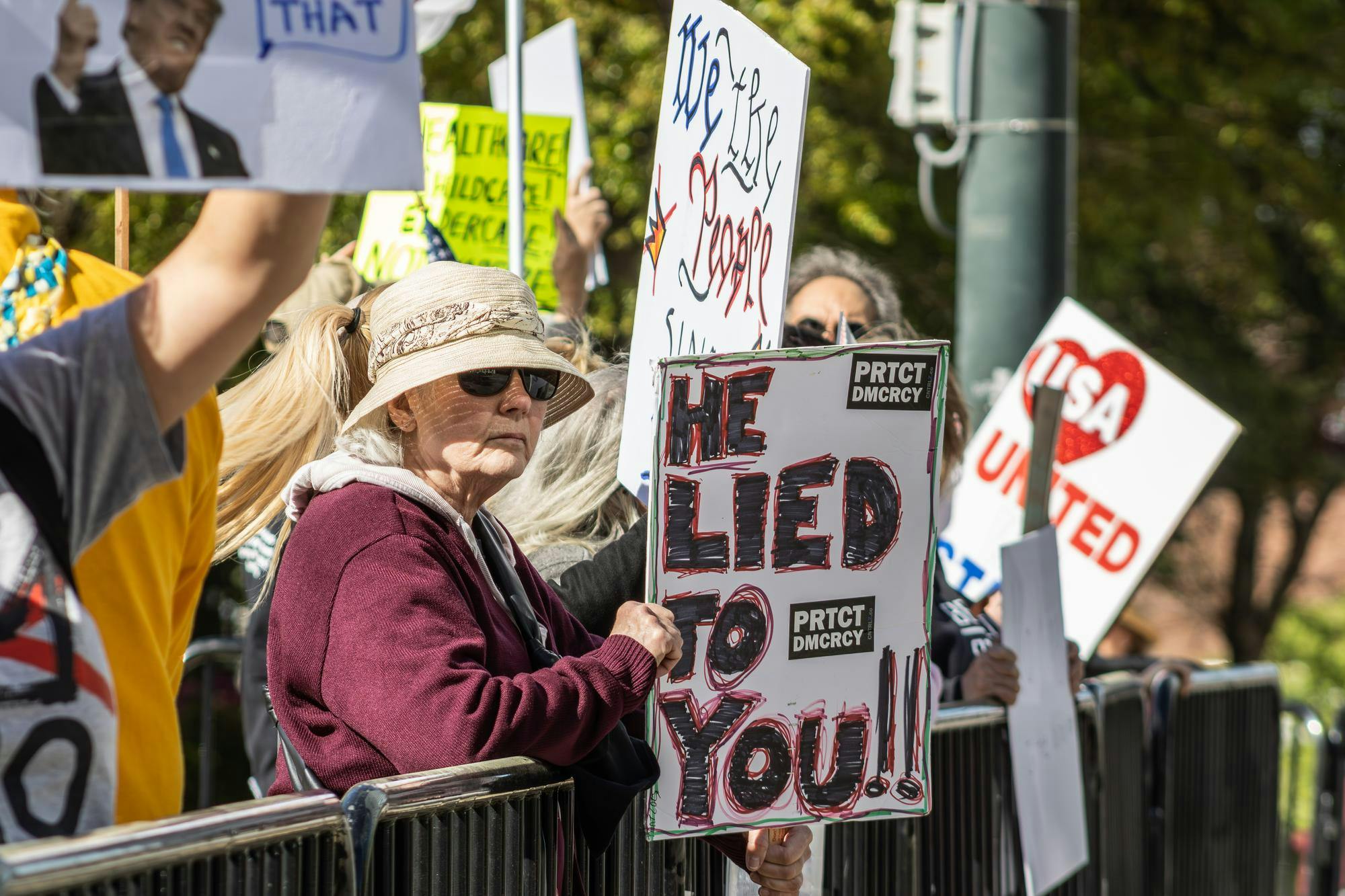 Individuals lift up their signs during the "No Kings" protest at the South Carolina State House on March 28, 2026. They spread their message to the cars that drive by on Gervais Street.
