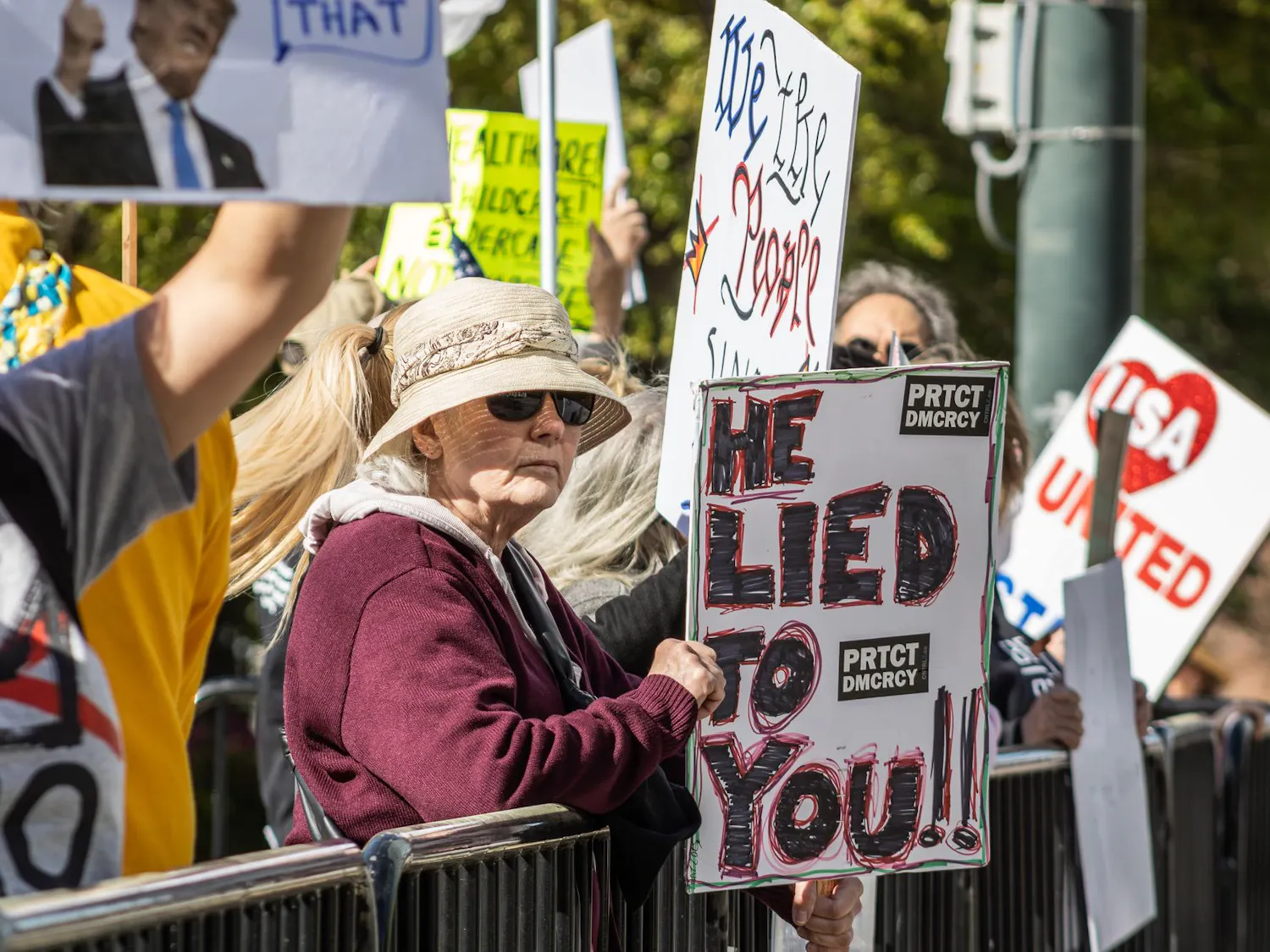 Individuals lift up their signs during the "No Kings" protest at the South Carolina State House on March 28, 2026. They spread their message to the cars that drive by on Gervais Street.