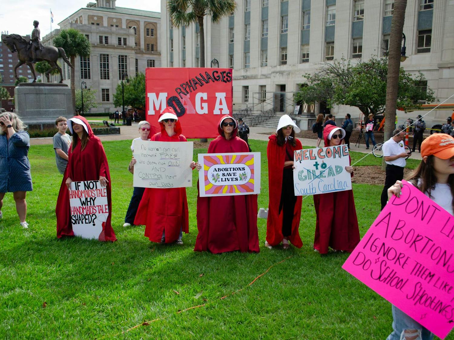 Protestors against Senate Bill 323 wave signs supporting legal abortion at the South Carolina State Capitol on Oct. 1, 2025. They are dressed as Handmaids from Margaret Atwood’s 1985 dystopian novel "The Handmaid’s Tale."