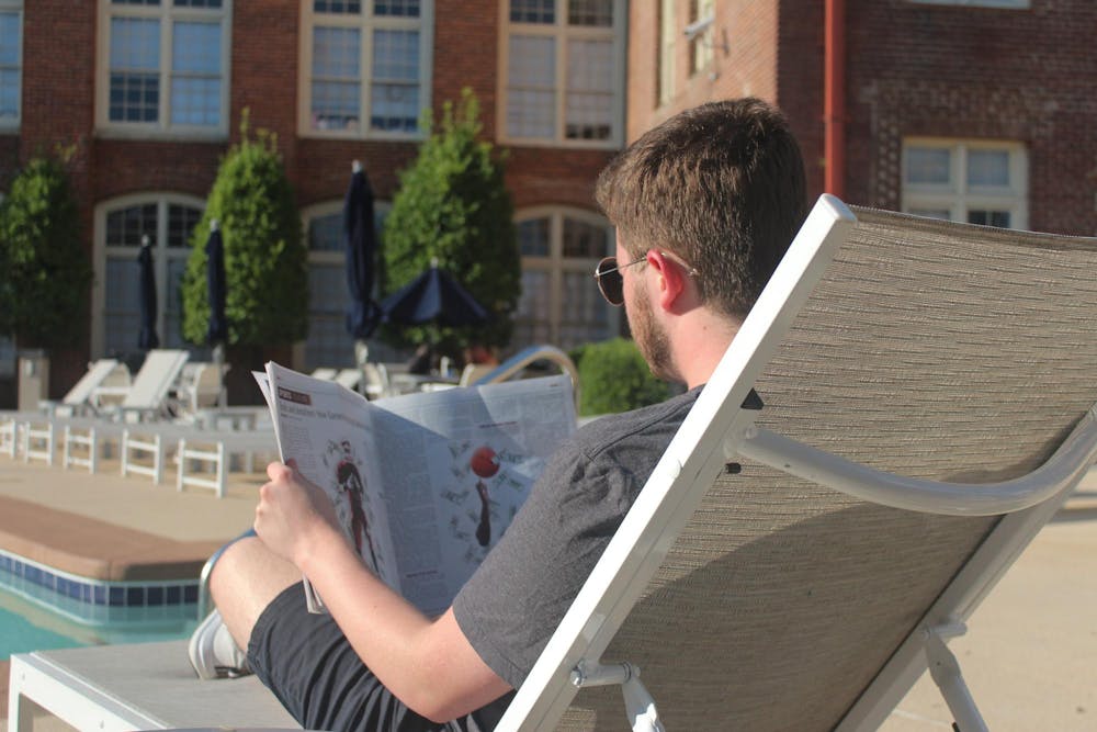 <p>A photo of a person relaxing by the pool and reading the latest print edition of The Daily Gamecock newspaper.</p>