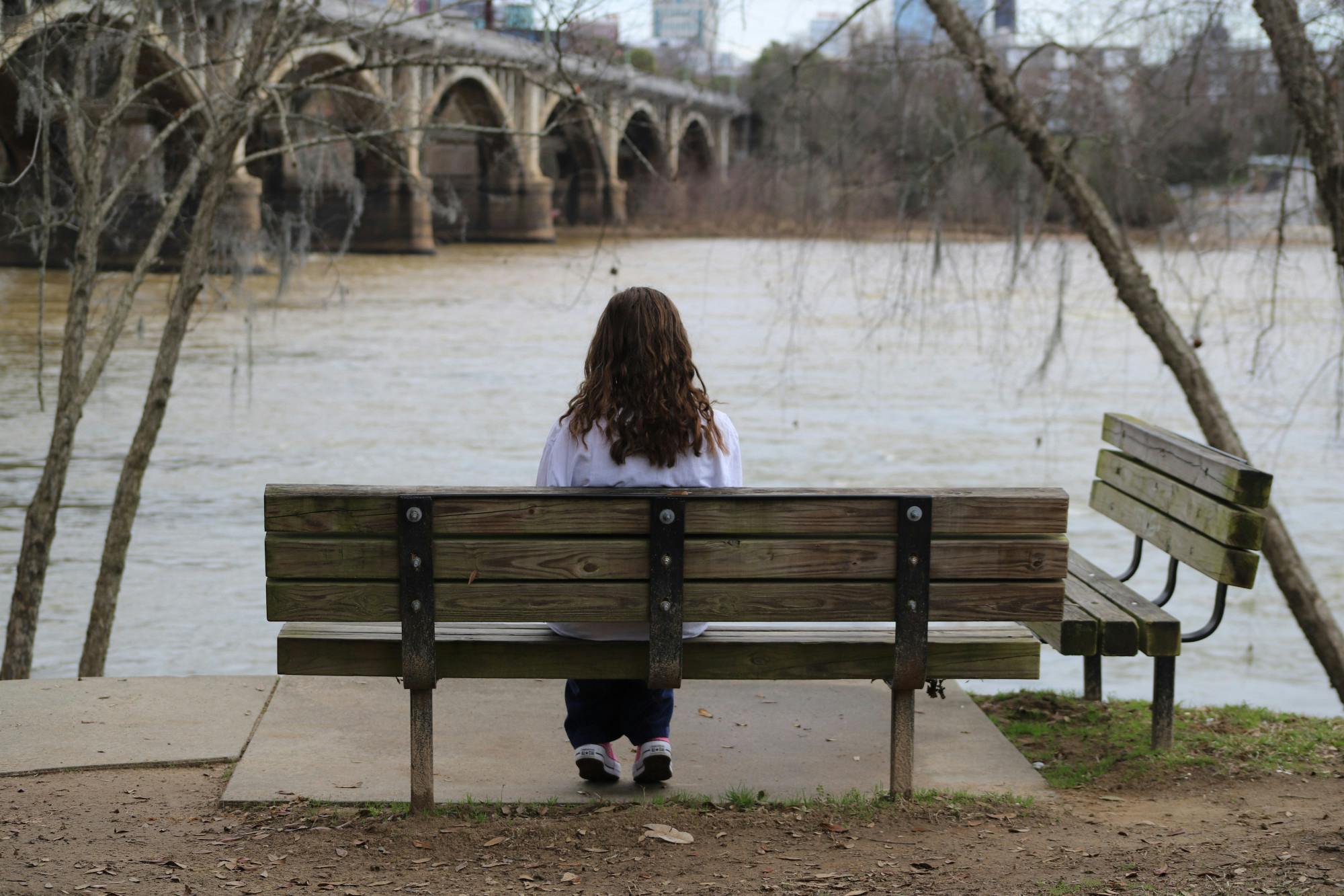 A person sits on a bench at The Riverwalk Park on Feb. 1, 2023. The park is a great place for students to go to relax and relieve some stress.