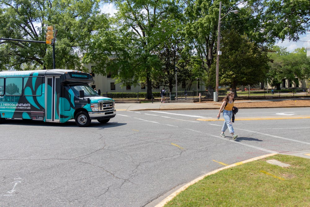 <p>A student crosses the street on the intersection of Sumter and Greene Streets while a shuttle attempts to turn on April 5, 2023. This intersection is often one of the busiest on campus and is often jaywalked by students despite frequent traffic.</p>