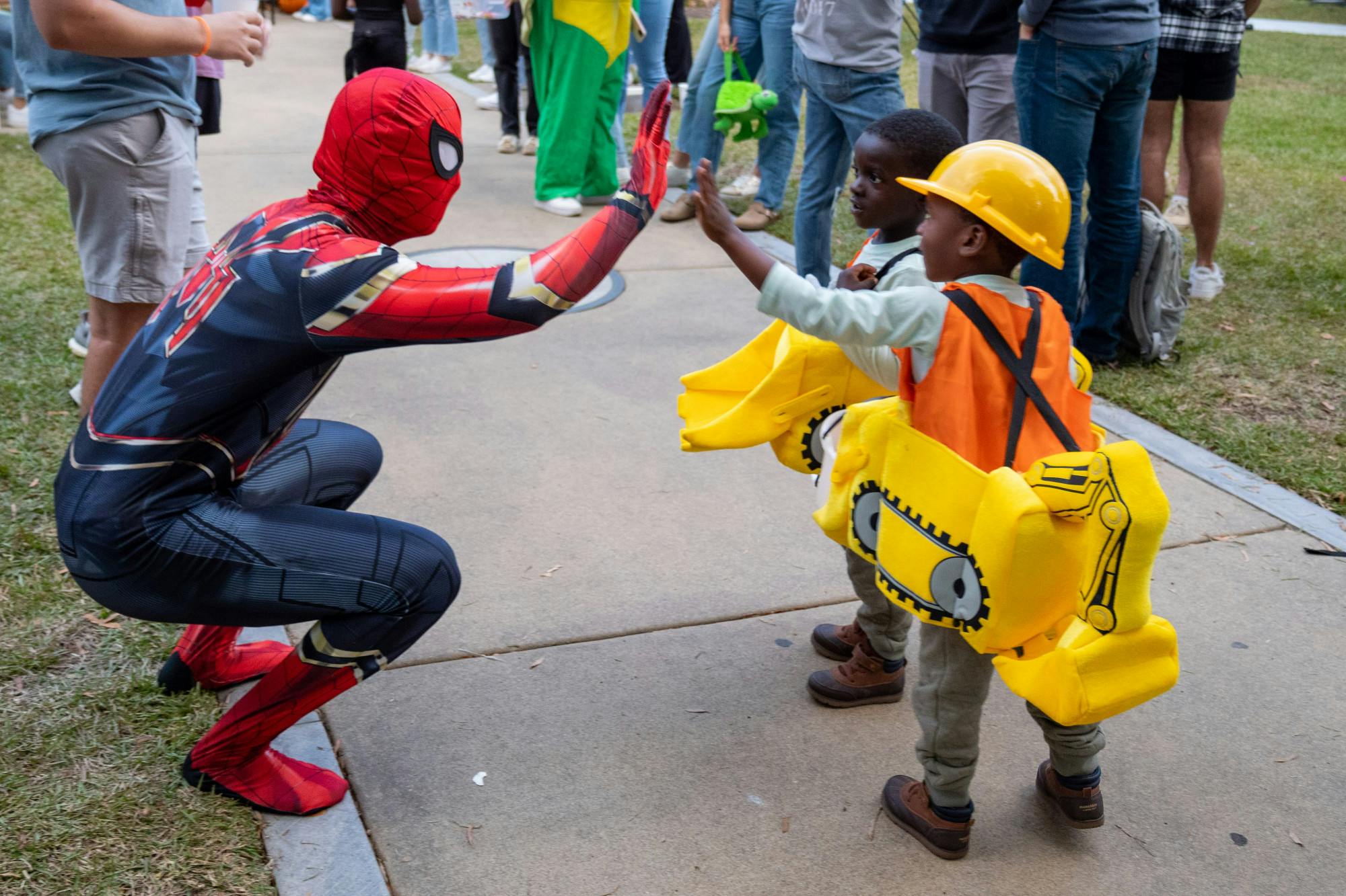 A USC Greek member high fives two young trick or treaters as they walk around collecting candy during a community event held by USC fraternities and sororities on Oct. 25, 2022. USC's annual Trick or Treat with the Greeks event serves as a community service event carried out by Columbia's Greek Life members in celebration of Halloween.