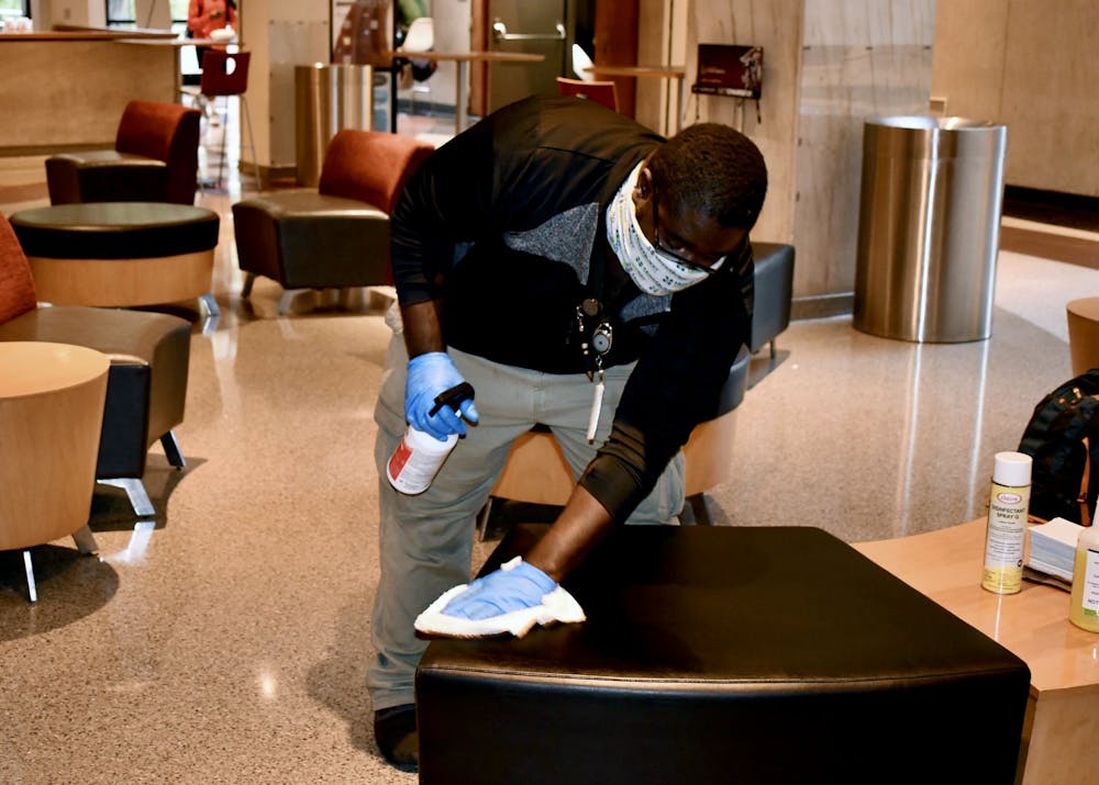 A member of the USC custodial staff cleans a seat in Russell House. 