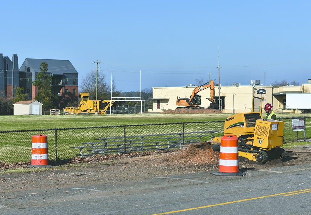 A worker grinds down a tree stump as construction begins on the new parking lot at the Greene Street Fields across from Colonial Life Arena.