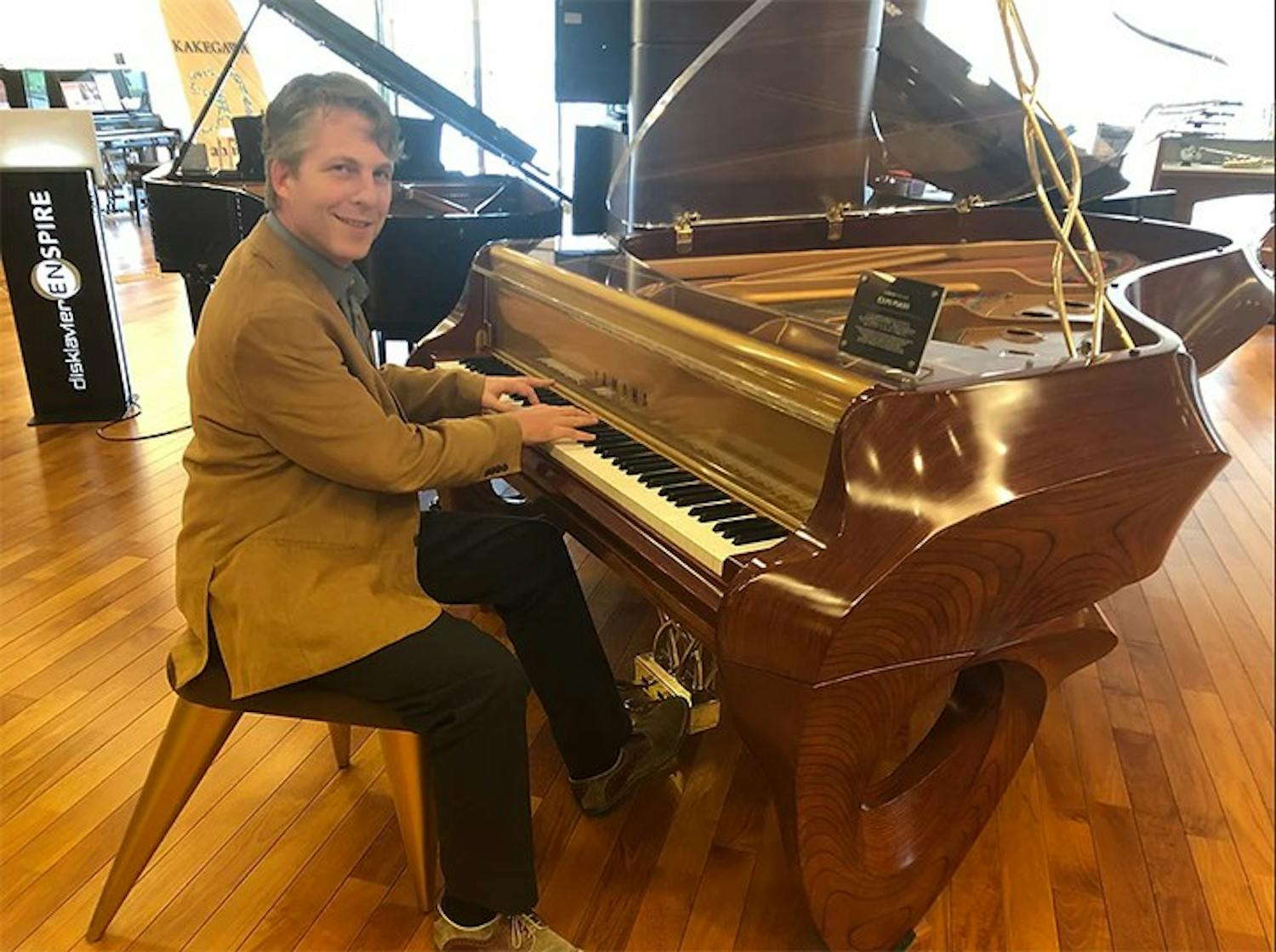 Music entrepreneurship professor David Cutler, whose book "The Savvy Musician" focuses on how to turn a musical education into a successful career, poses with a piano.