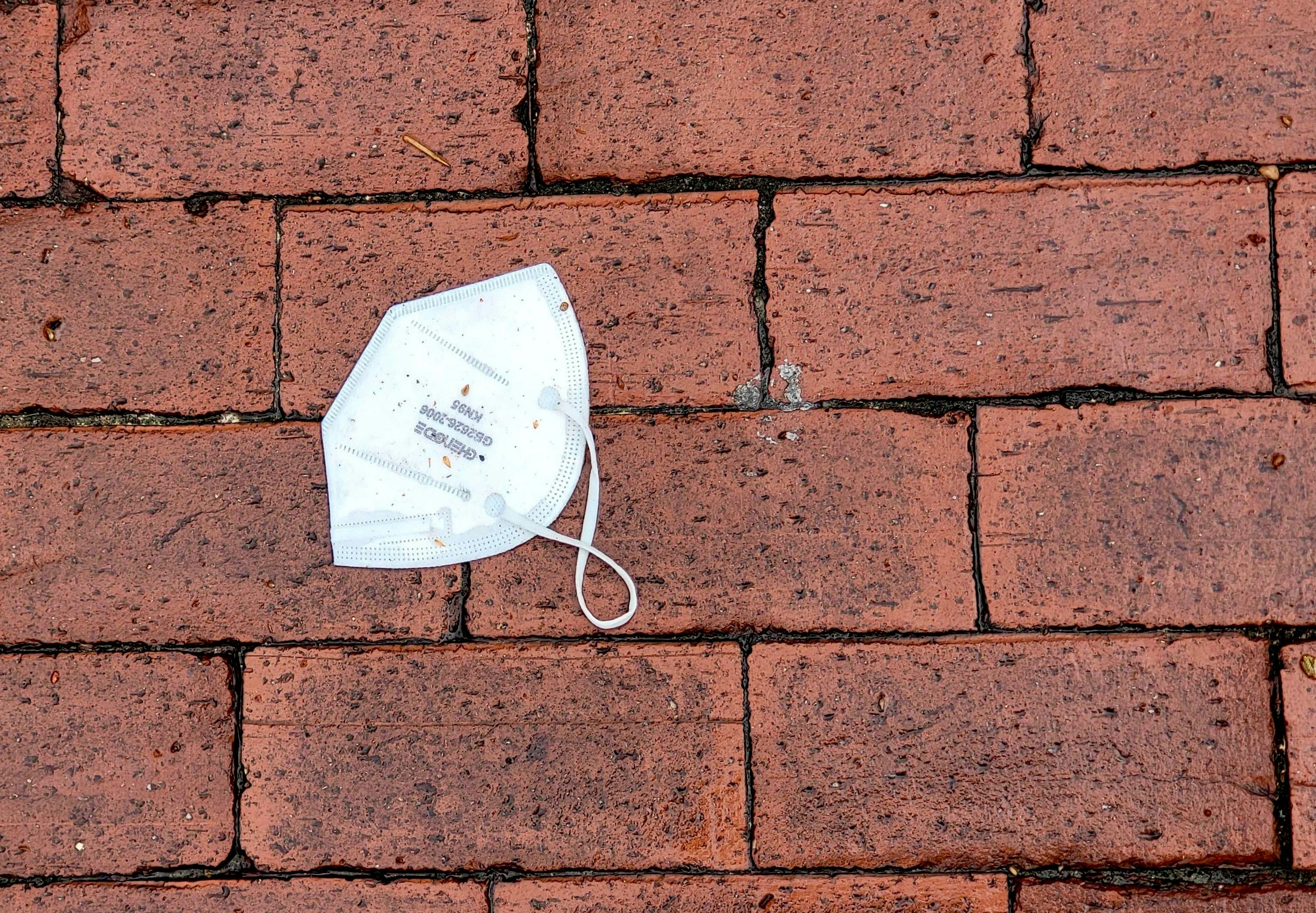 A used KN95 mask on the wet bricks outside Russell House on Mar 16, 2022.