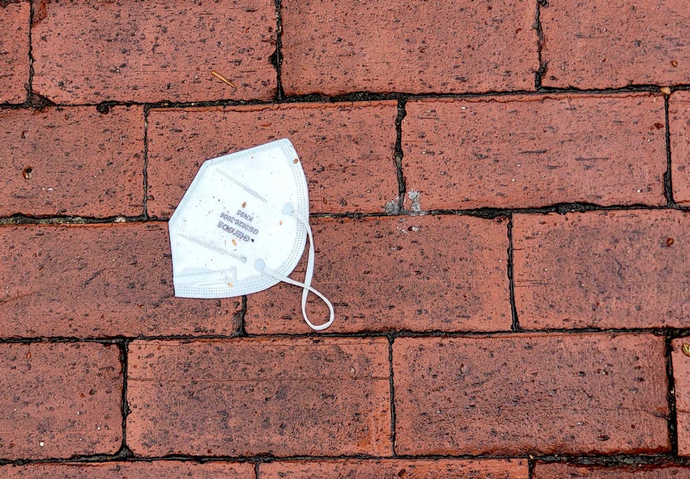 A used KN95 mask on the wet bricks outside Russell House on Mar 16, 2022.
