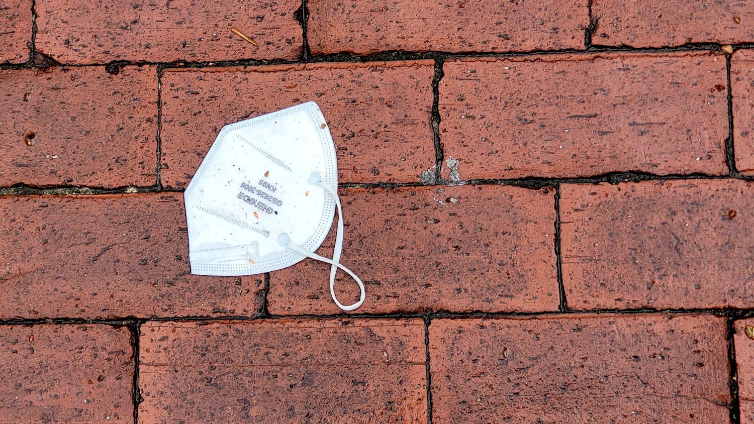 A used KN95 mask on the wet bricks outside Russell House on Mar 16, 2022.