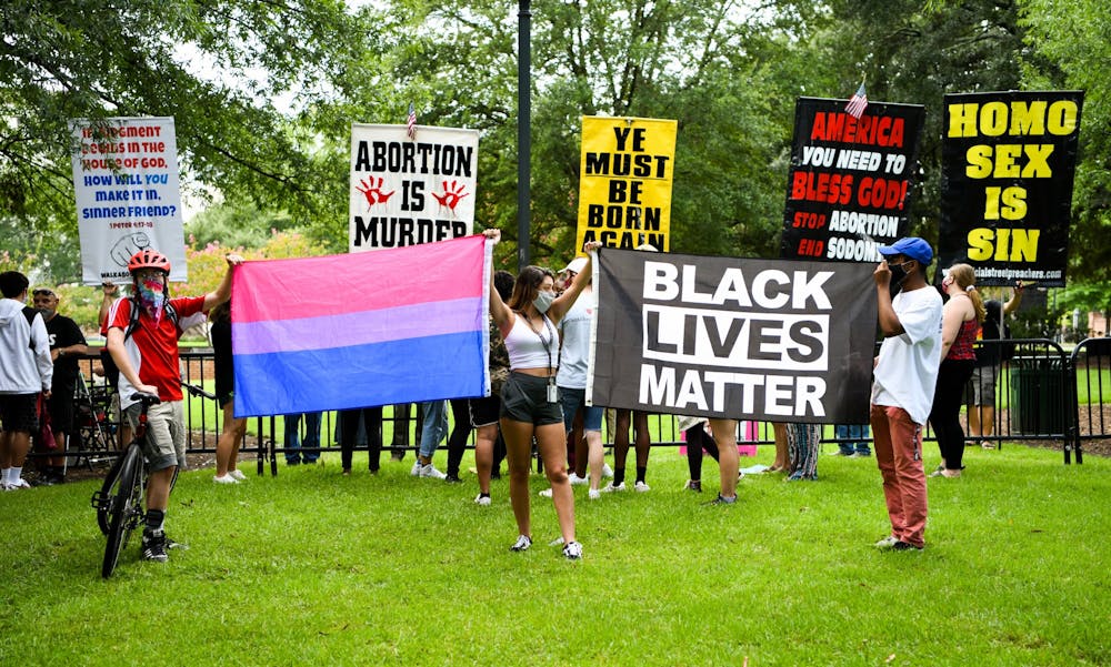 <p>University of South Carolina students hold a transgender pride flag and a Black Lives Matter flag in front of protestors on campus on Aug. 26, 2020.</p>